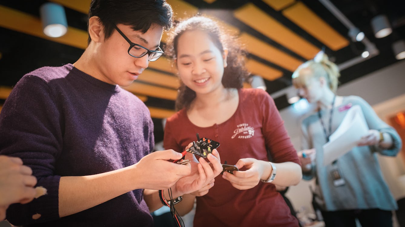 Photograph of a young man and woman working together to create an electrical component.