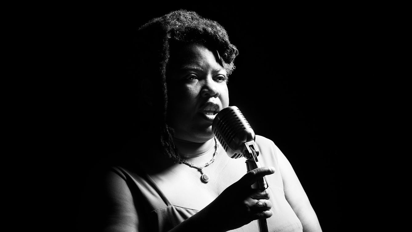 Black and white photographic portrait of Cheryl Martin performing holding a microphone. 