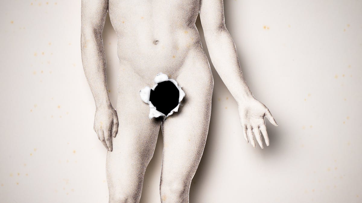 Photograph of an illustration of a naked man where the body of the man has been cut out and lifted above the background. Where the man's genitals should be there is a black hole with the torn edges folded forwards.
