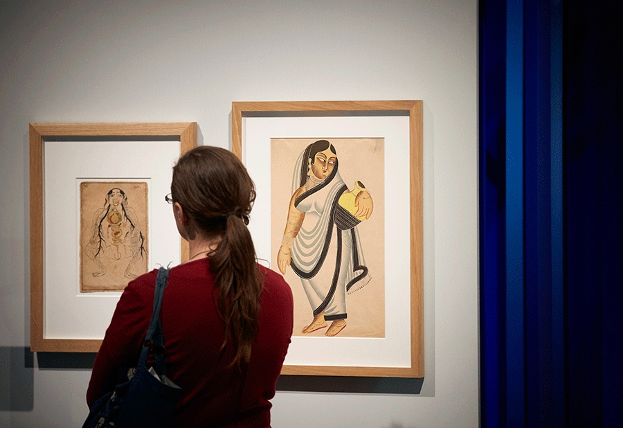 A visitor looks at two watercolours from the 19th century: one of the viscera with a fetus in utero and one of a woman holding a pitcher