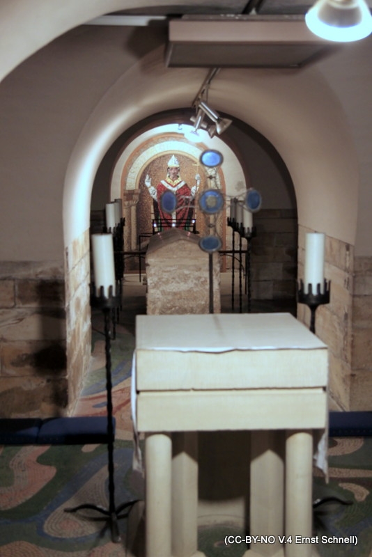 The photo shows the sarcophagus of Archbishop St. William Fitzherbert of York between an altar and a mural of his image in the crypt of York Minster.