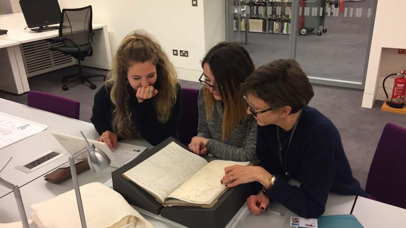 Three young people looking through a manuscript from the Wellcome Collection