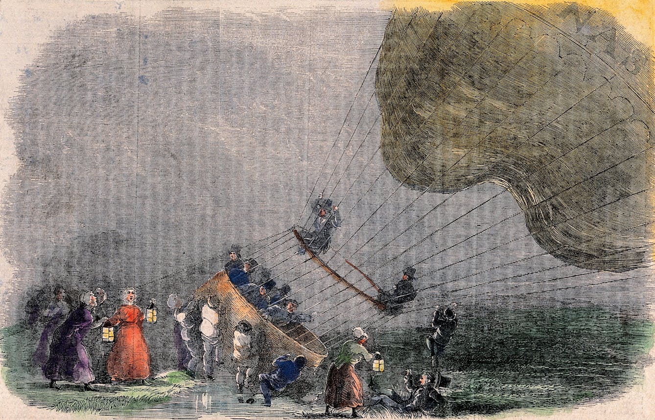 A hot-air balloon has landed in stormy weather, a crowd of people have brought lamps and are helping the aeronauts.