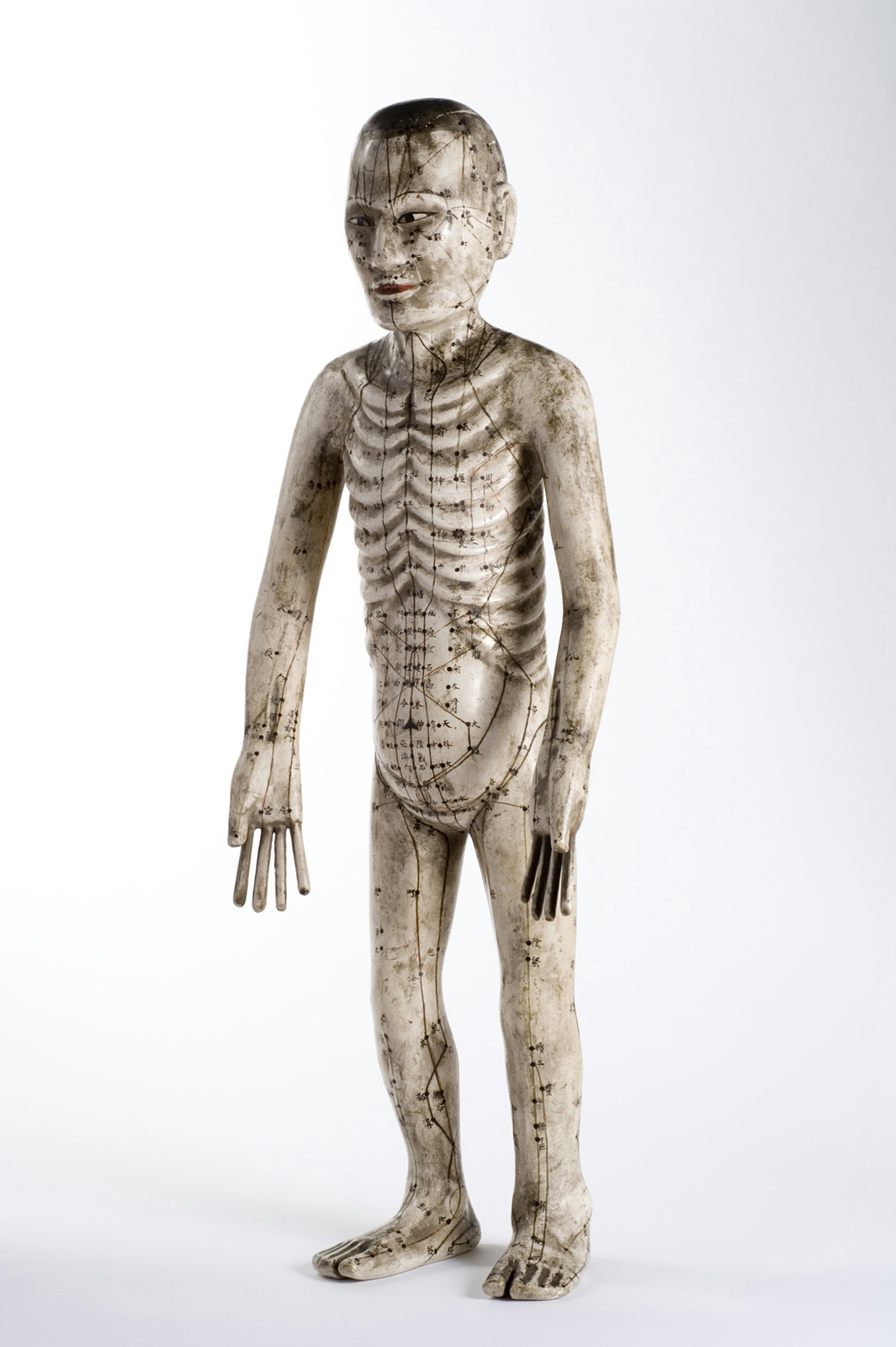 An image of a human figure made from papier mache with acupuncture points marked on it.