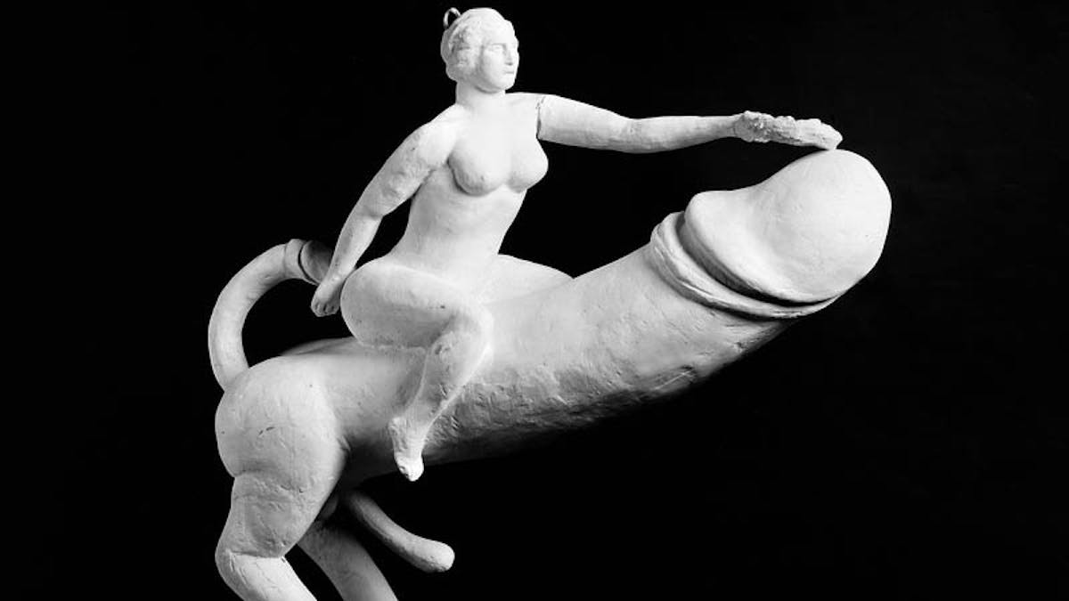 Image of a white plaster cast phallic object showing a woman astride a giant penis.