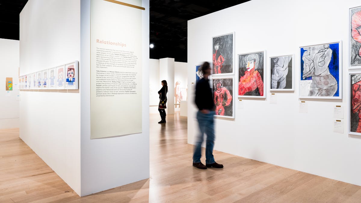 Photograph of visitors exploring the exhibition, Souzou: Outsider Art from Japan, at Wellcome Collection.