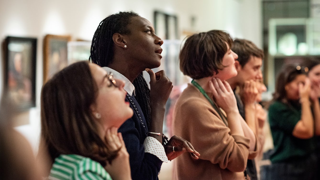 Image of people standing using their voices and touching their throats