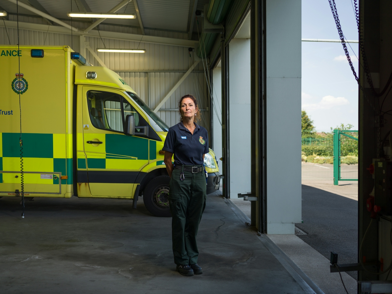Photographic full length portrait of Mandy English, a paramedic, in her ambulance station.