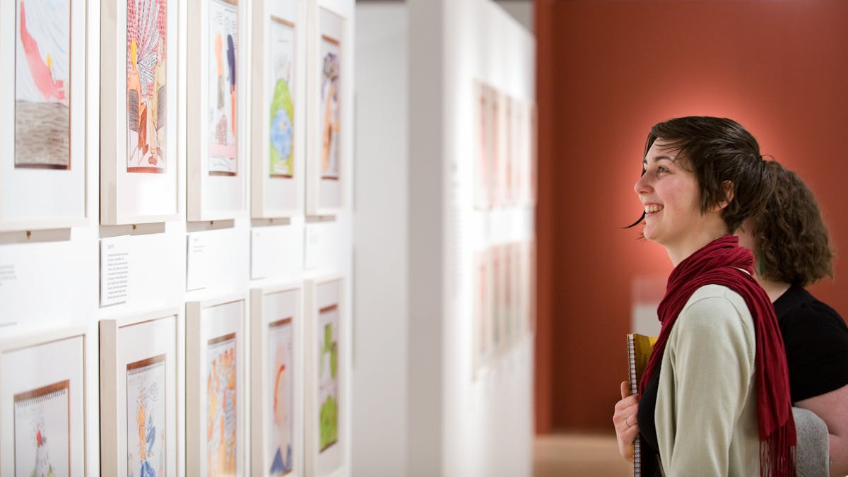 Photograph of visitors exploring the Bobby Baker’s Diary Drawings exhibition at Wellcome Collection.