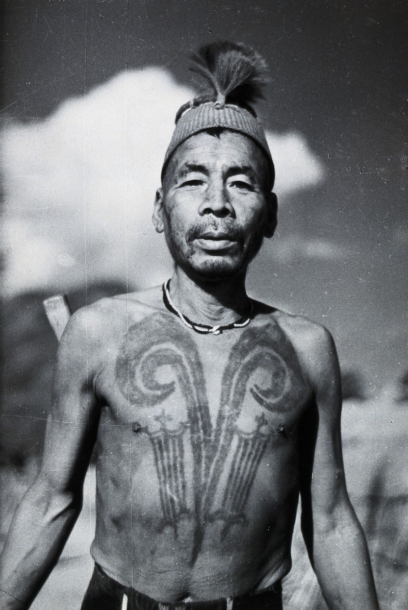 Black and white photo of a man with a chest tattoo