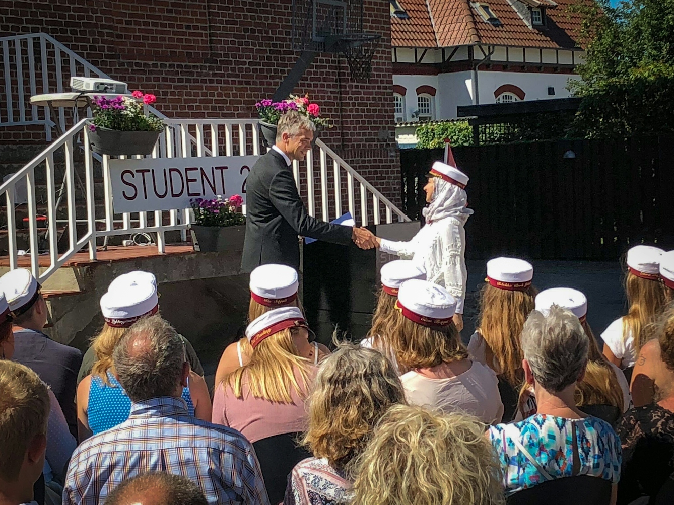Photograph of a young woman shaking the hand of a man as part of a student graduation ceremony.