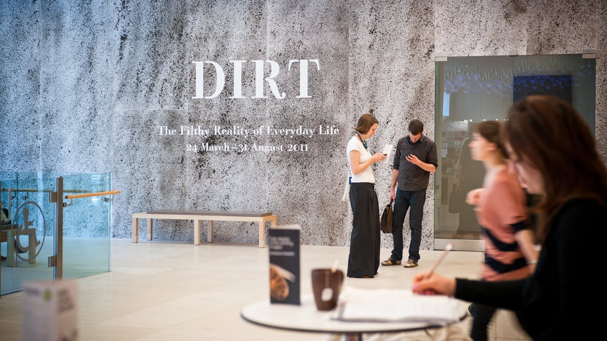 Photograph of the entrance to the exhibition, Dirt: The filthy reality of everyday life, with visitors standing outside.