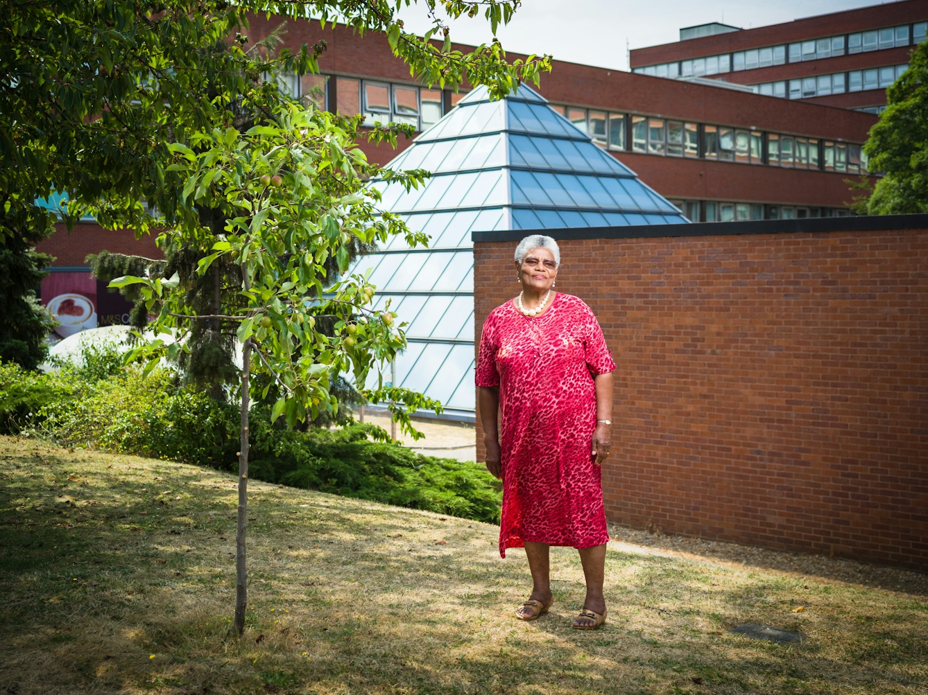 Photographic full length portrait of Cecilia Brown, nurse, outside St George's University Hospital, London.