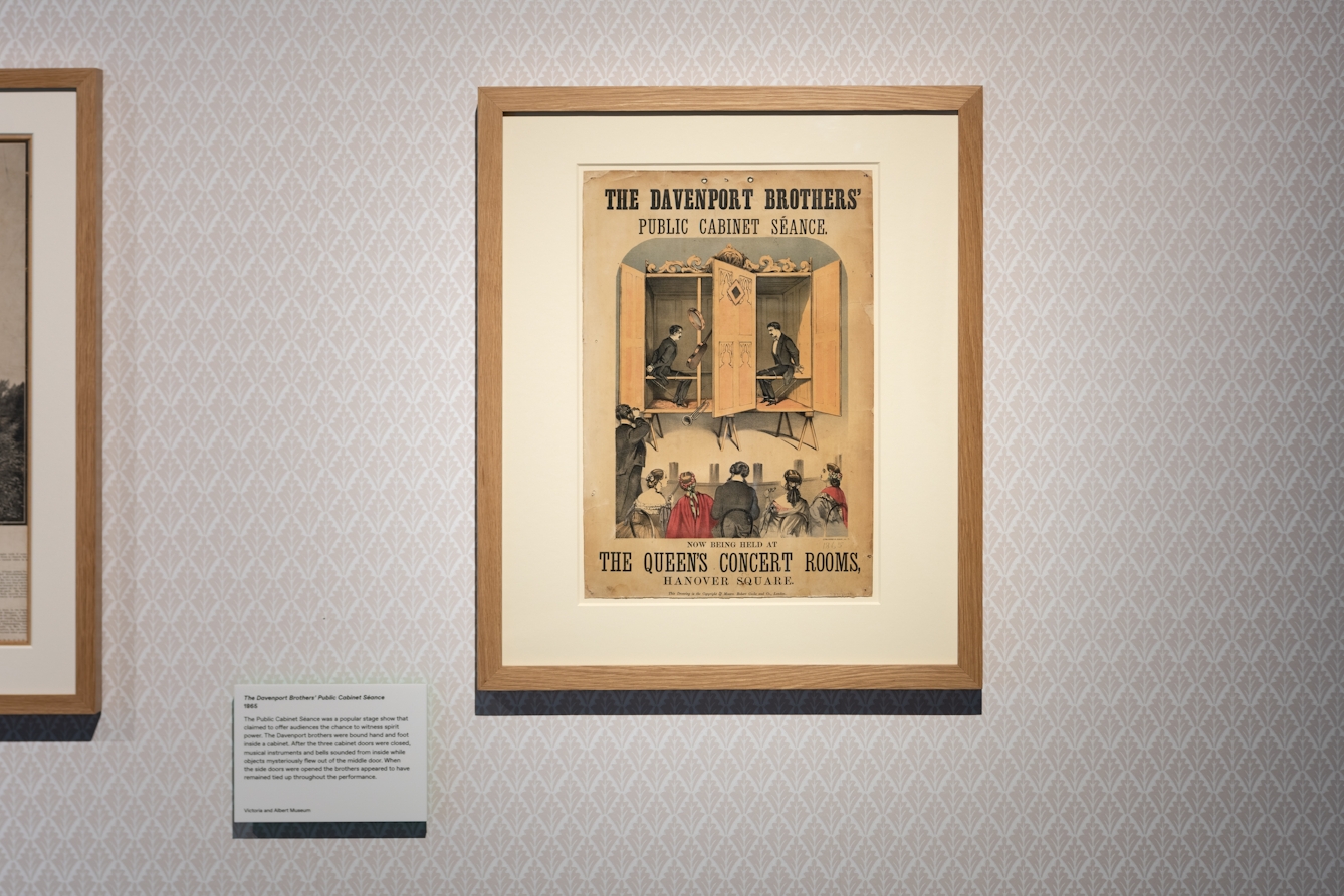 Photograph of a framed poster titled, 'The Davenport Brothers' Public Cabinet Séance', as part of the Smoke and Mirrors exhibition at Wellcome Collection.