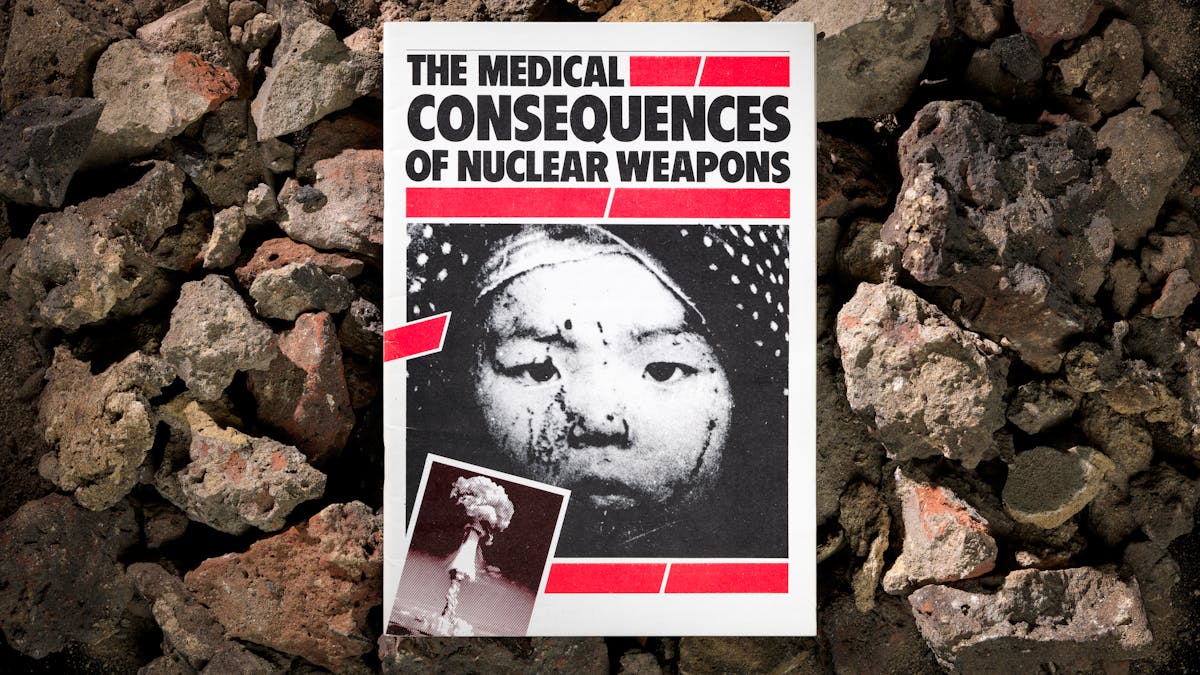 Photograph of a booklet titled, The Medical Consequences of Nuclear War, against a background of building rubble.
