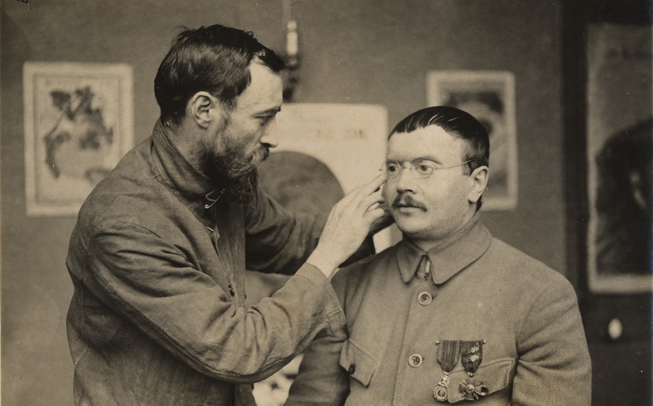 A man adjusts the spectacles on another man's face.