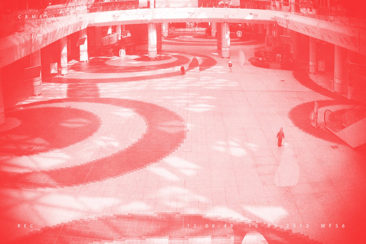 Pixellated photograph from a shopping mall security camera, where all adults have been crudely 'Photoshopped' out of the image, leaving one remaining child. The image has a red/pink tone applied to it.