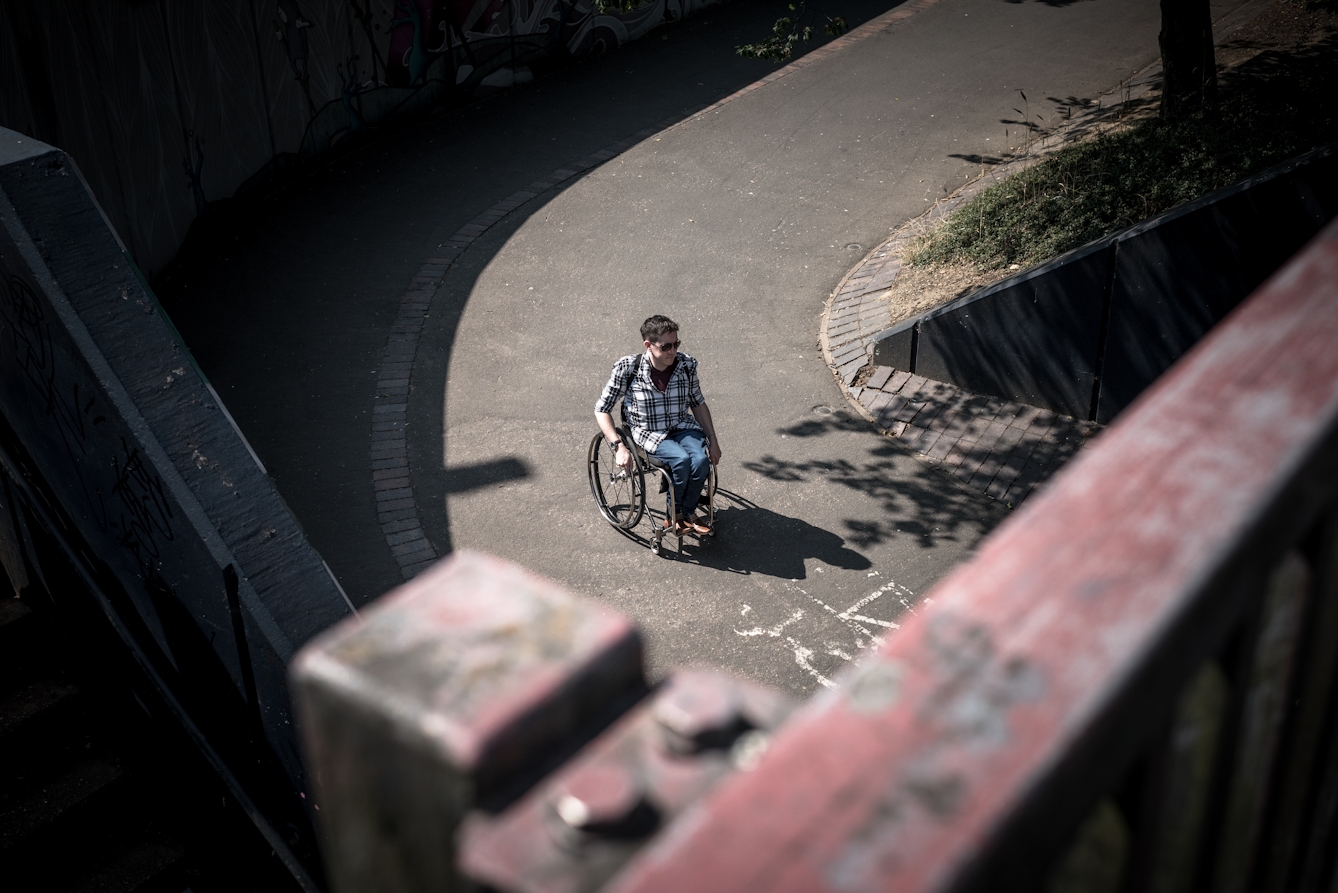 Photograph of a man travelling down a footpath in his wheelchair.