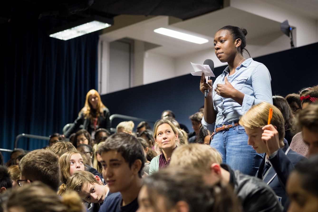 Photograph of a young woman talking into a microphone at an event.