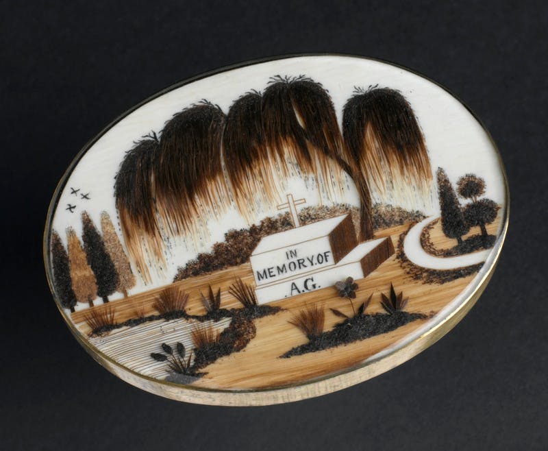 Image of a brooch decorated with human hair forming an image of a tombstone under a tree.