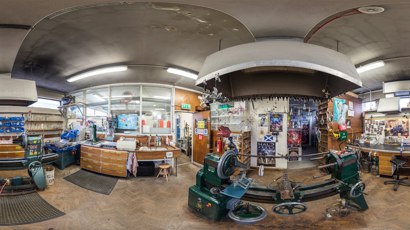 A distorted fish-eye photograph of a workshop with various machinery and posters.