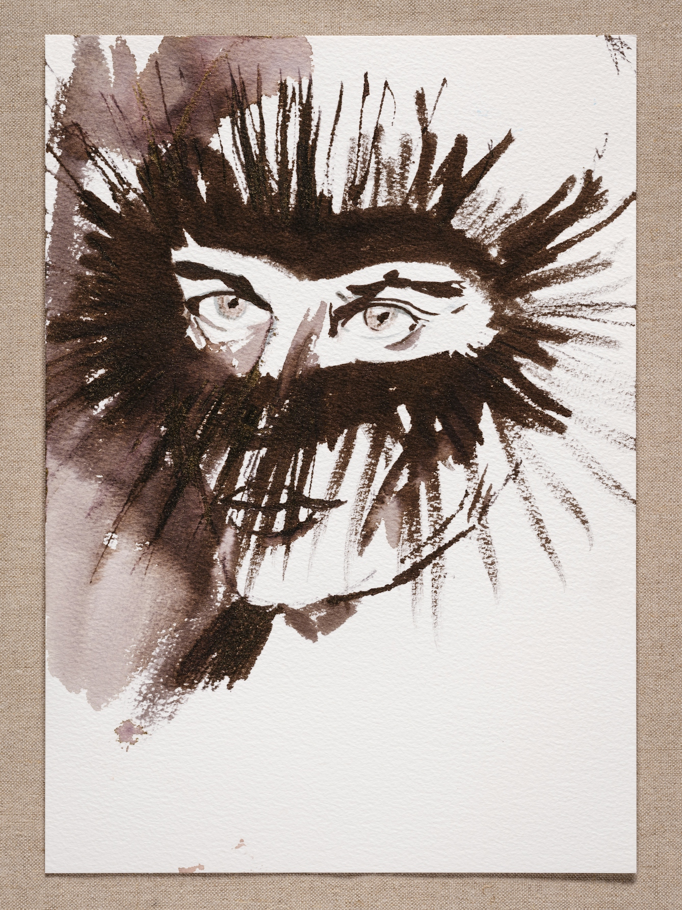 Watercolour painting resting on a brown fabric background. The watercolour shows a face painted in brown tones. A ring of streaks radiates from the eyes, accentuating their presence.