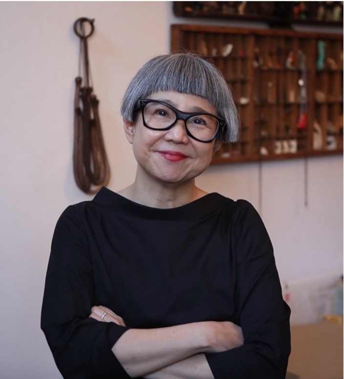 Headshot of Stacy Makishi, smiling with her arms folded