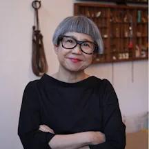 Headshot of Stacy Makishi, smiling with her arms folded