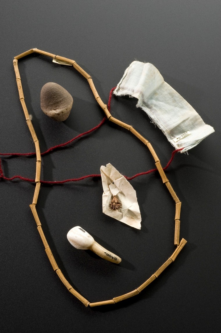 A configuration of several objects including a small piece of flint,a piece of turf, a wooden necklace and a calf’s tooth