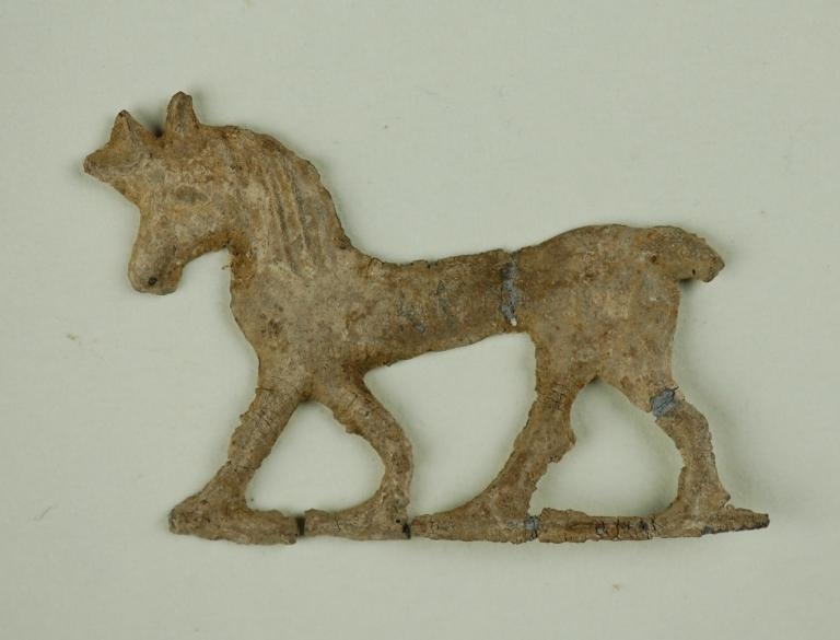 A photograph of a lead horse votive offering from the Sanctuary of Artemis Orthia. The horse is in profile to its right and has all its legs complete.