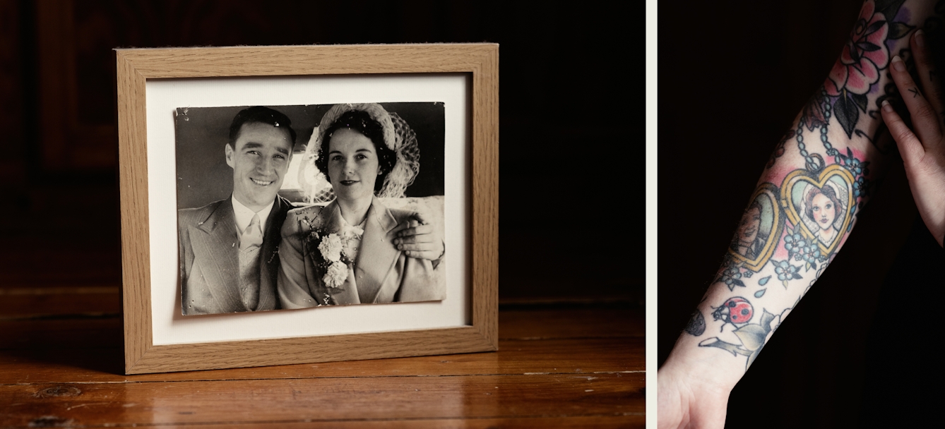 Photographic diptych made up of one landscape orientation and one portrait orientation image. The image on the left shows a wooden tabletop on which a small framed photograph is propped up. The black and white print is in a wooden frame and shows a man and a woman on their wedding day, smiling to camera, The man on the left has his arm around the woman. The image on the right shows a close-up of a woman's right forearm against a black background. The woman's arm is adorned with a large tattoo which extends from her wrist up past her elbow. In the centre of the tattoo design is a representation of the couple in the wedding photo, the man and the woman set in separate heart locket shapes.