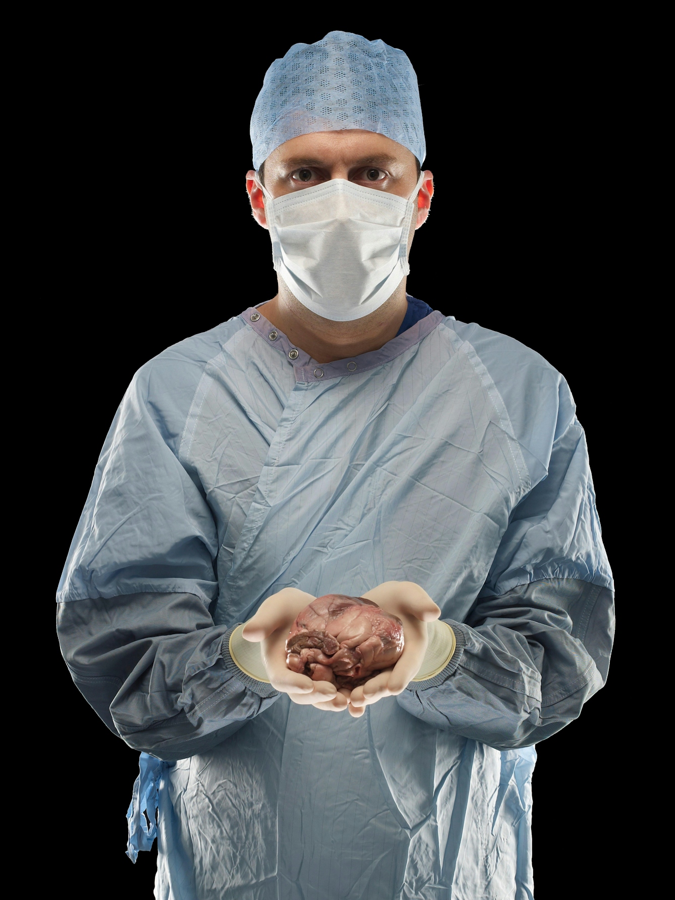 A photograph of a surgeon in scrubs, holding out a heart in the palms of his hands 