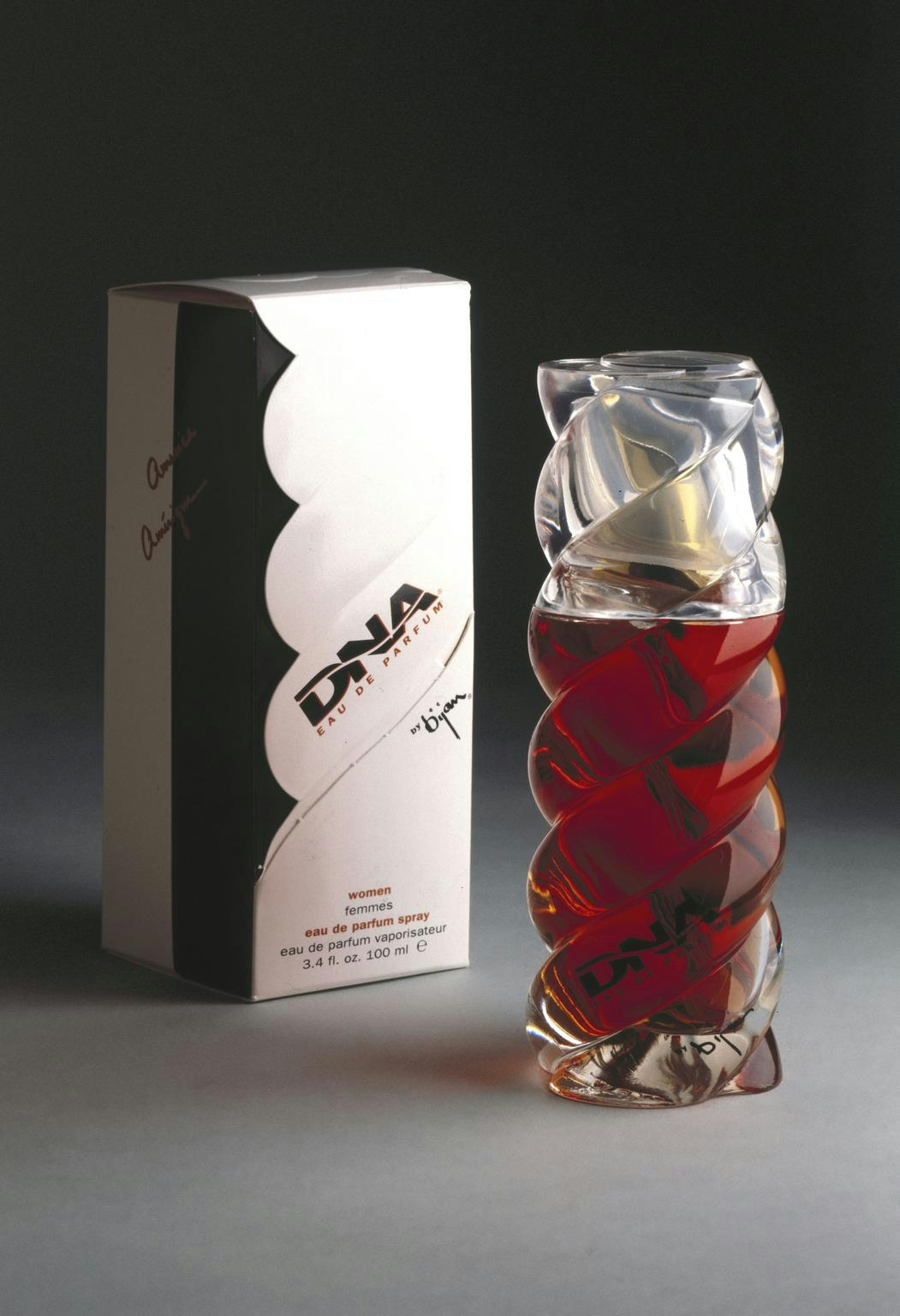 Photograph of a glass helical-shaped bottle of 'DNA eau de parfum', standing in front its packaging, prminently labelled 'DNA'.