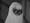 An alien creature with a blanket over its head looks at the viewer through a hole cut for its eyes.