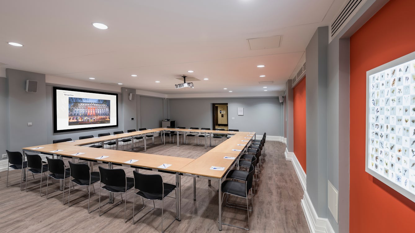 Photograph of the Burroughs room at the Wellcome Collection. 

Photograph shows a boardroom set-up and a presenting screen at the front of the room. 
