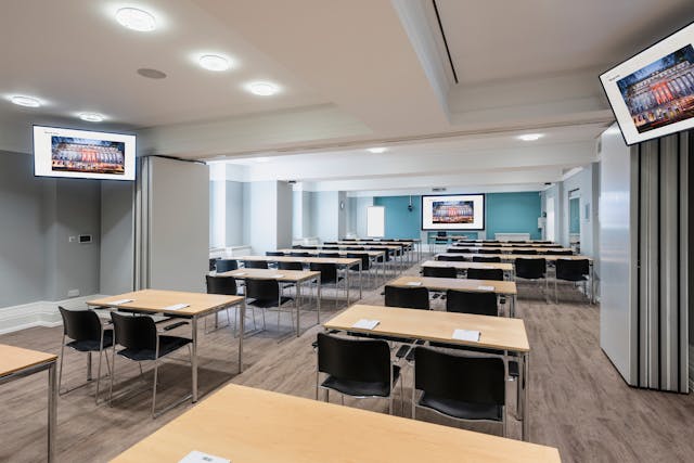 Photograph of the Franks and Steel room at the Wellcome Collection. 

Photograph shows a classroom set-up., with desks spaced apart and presenting screens around the outside of the room. 