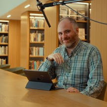 Photo of Paul Craddock sitting in a library in front of an iPad
