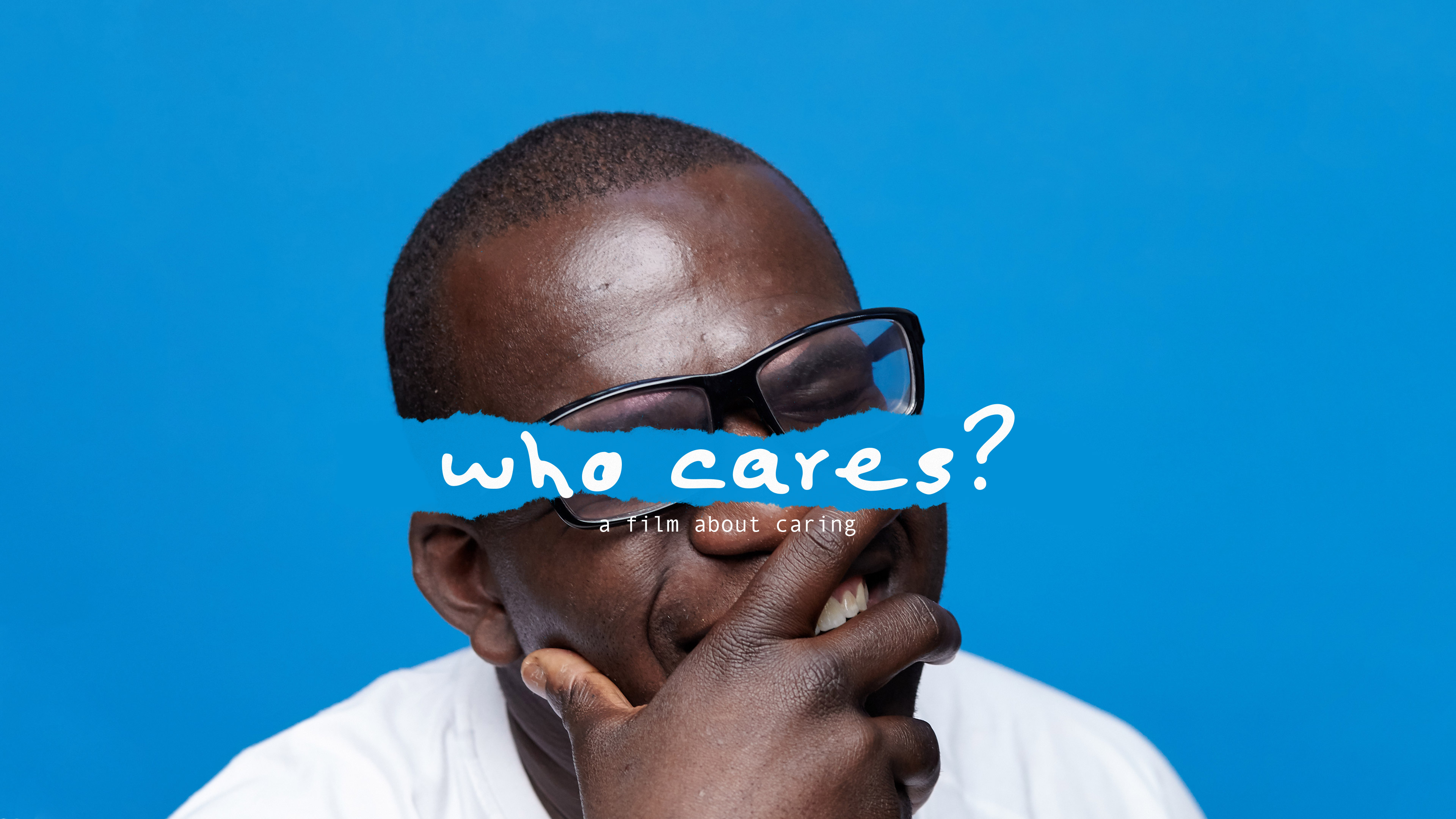 Portrait of Michael Prempe who is wearing glasses and holding his hand to his mouth. The words "Who Cares? a film about caring" appear over his eyes