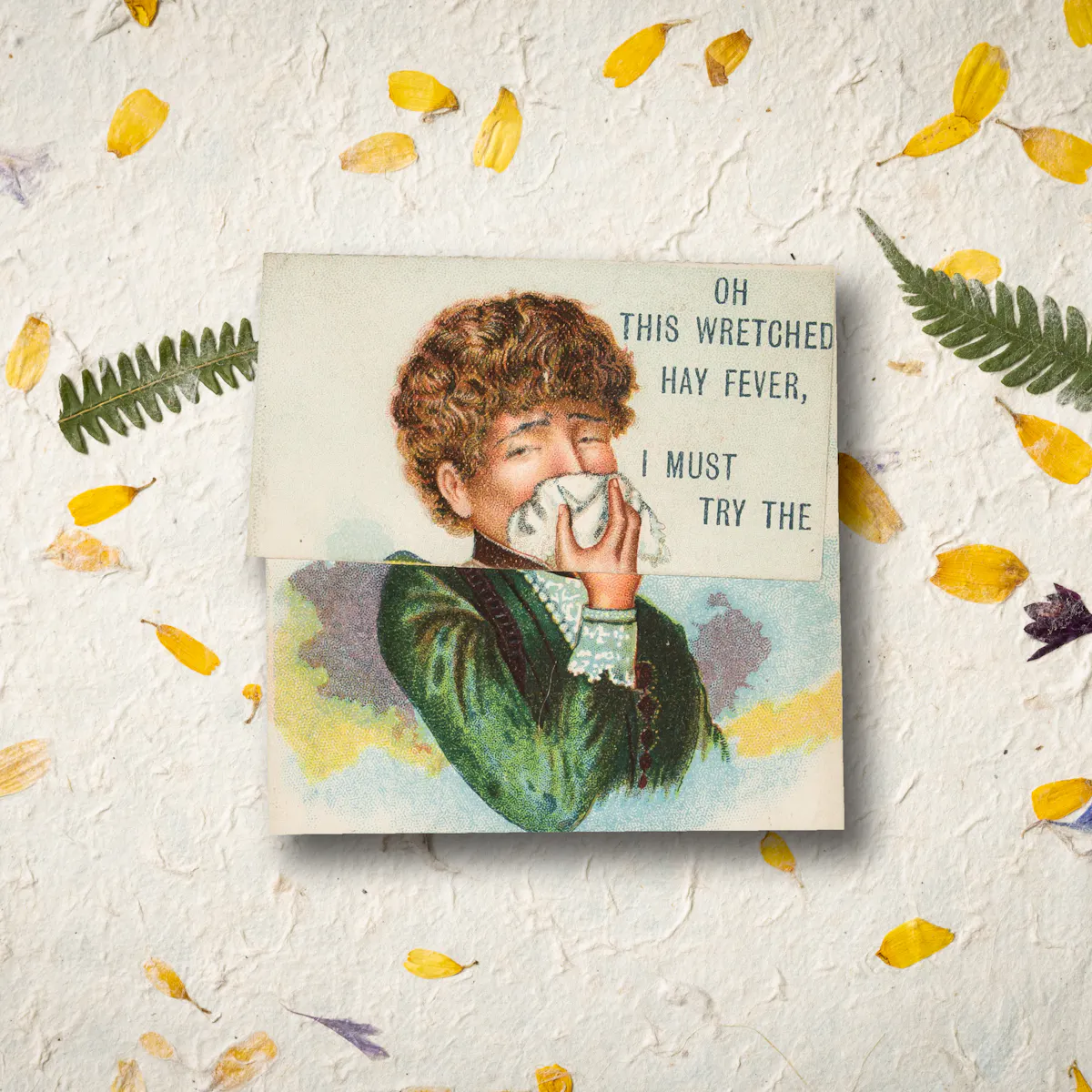 An image of 19th century advertising card for medicine, the card shows a woman with brown, wavy hair in a green dress holding a handkerchief to her nose, with an expression of suffering on her face. Behind the card is a background of yellow, blue and violet petals as well as green leaves.