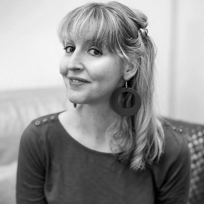 Head and shoulders photograph of a woman with long fair hair wearing a large circular earring 