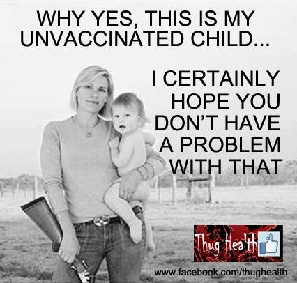 A woman holding a large gun dares you to vaccinate the child she is holding.