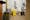 Photograph though the doorway of an accessible toilet showing part of the door and doorframe, along with the contents of the room, toilet, basin and sanitary bins. The room looks run down and dirty. To the left of the toilet is a yellow, caution wet floor sign.