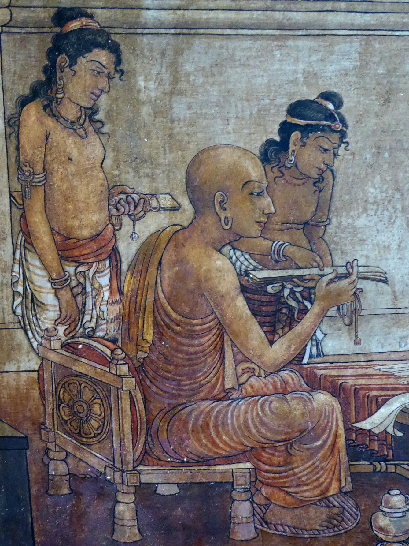 A seated Buddhist monk examines a palm leaf manuscript, as two young men, both standing, join him. One has another palm leaf manuscript in his hand. Detail of Kelaniya Temple painting.
