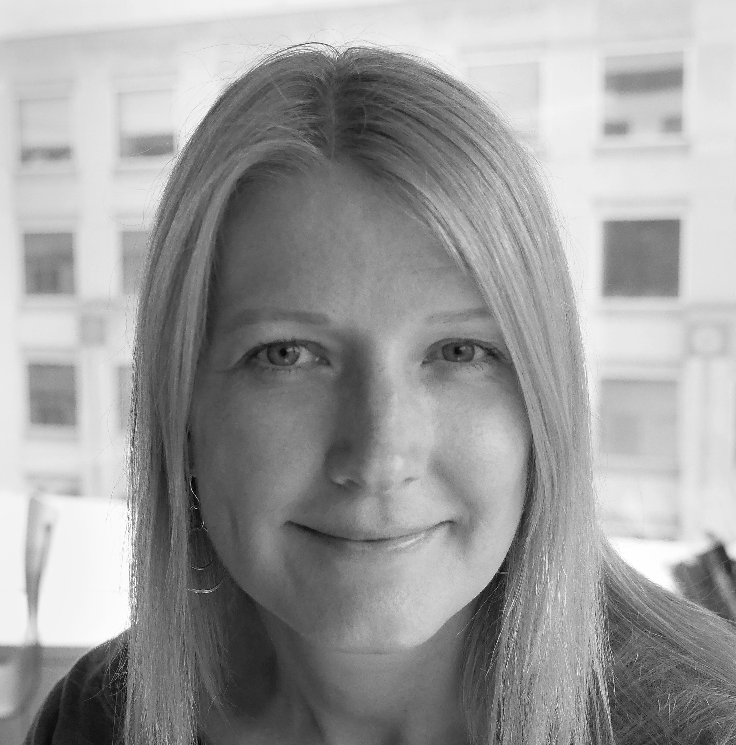Black and white photograph of a young woman with long blond hair looking straight at the camera and smiling.