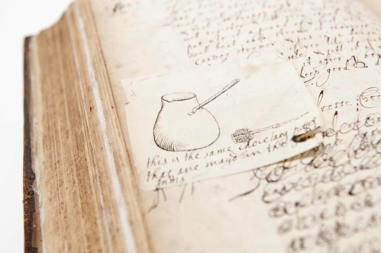 Photograph of a hand-drawn illustration, stuck into a book on a slip of paper, showing a pot and whisk used to prepare chocolate.