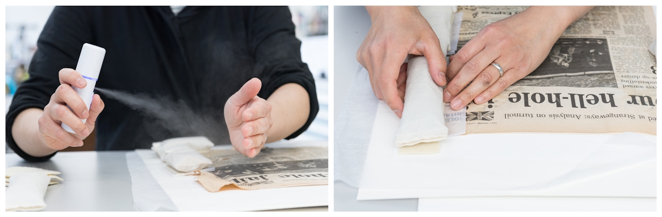 Photographic diptych. The image on the left shows a close-up of an individual seated at a grey conservation table. On the table is a creased newspaper cutting. The individual is spraying the newspaper with a fine mist of water from a white dispenser. Their other hand shields the area of the paper which is not crease. The image on the right shows the same sheet of newspaper, but here the now flat edges are being weighed down with white weights.