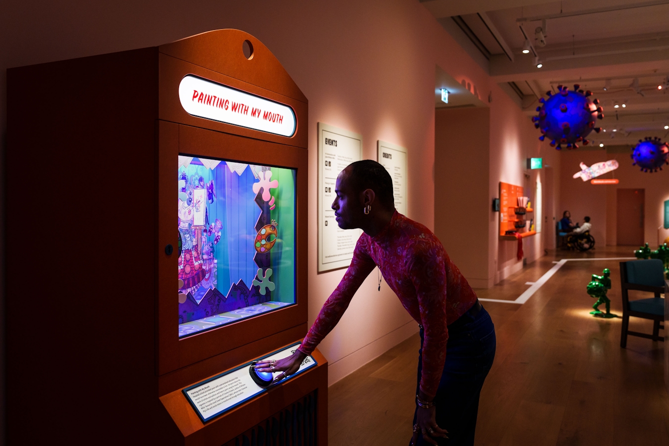 Photograph of a person pushing the button on the front of a display box with a glass front. The box contains a diorama.