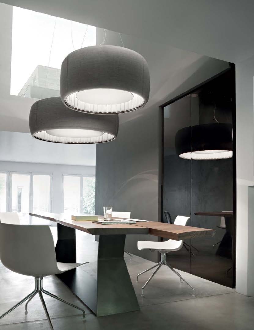 Colour photograph of a room with table and chairs below large round grey light fixtures, which are Silenzio lights by Luceplan.