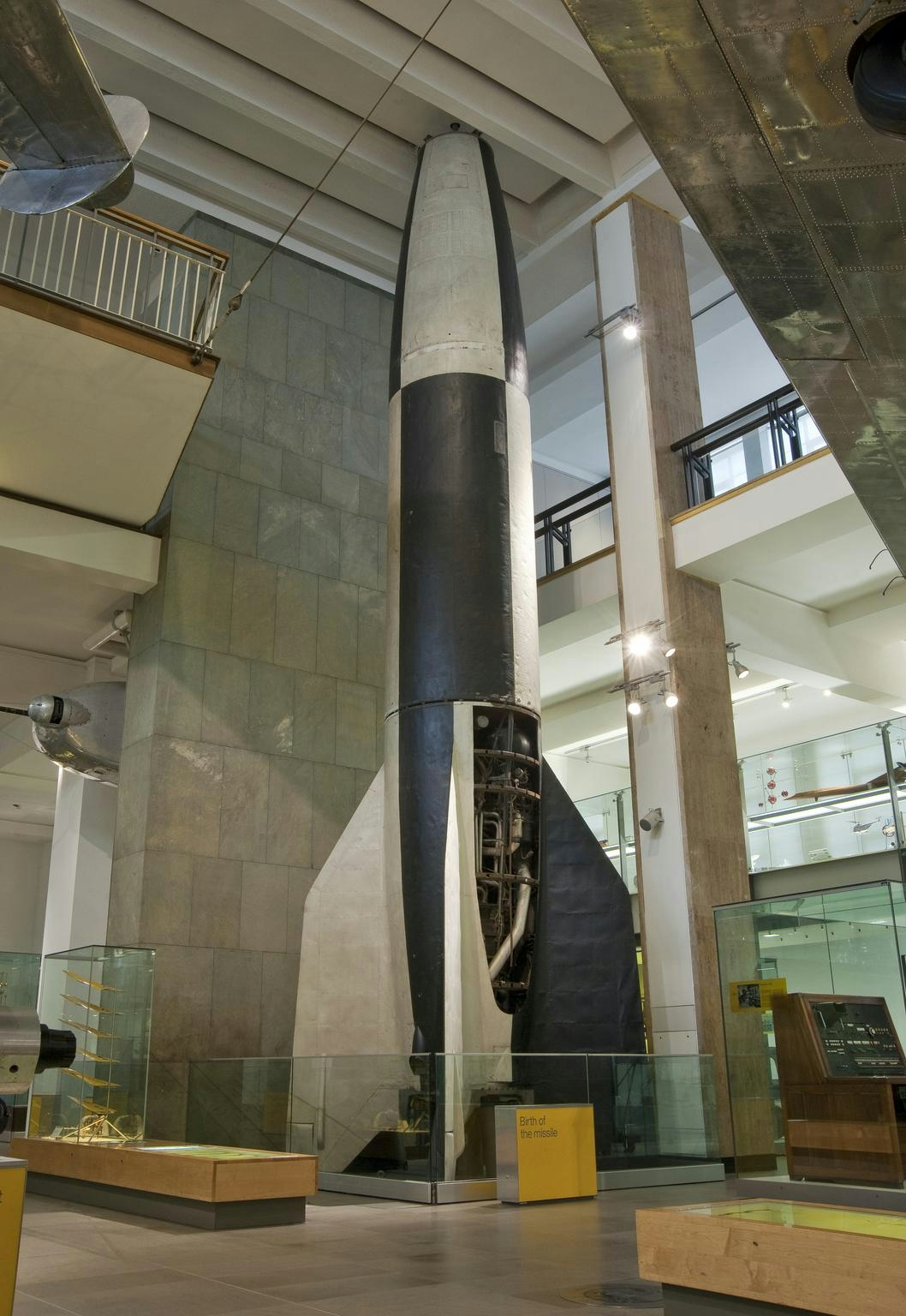 Colour photograph of a large black and white rocket, pictured on display inside a museum.