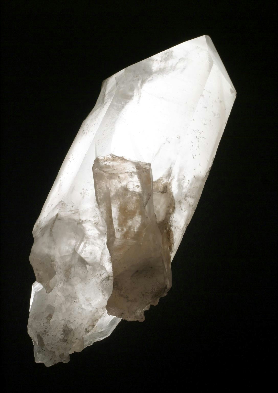 Photograph of a shaped piece of quartz against a black background. The quartz is lit from behind making it glow from within.